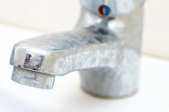 Llave de lavabo cubierta de manchas blancas de cal.